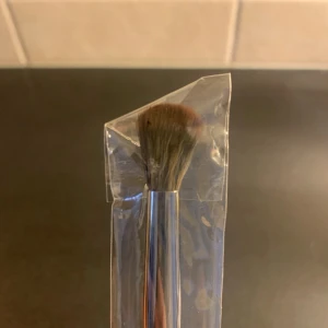 Ögonskuggsborste med trähandtag - Snygg ögonskuggsborste med mjuka, täta borst i brunt och ett elegant träfärgat handtag. Borsten har en rundad form som gör det enkelt att blenda ögonskugga. Kommer i genomskinligt plastfodral. Perfekt för dig som vill ha precision i din sminkning.