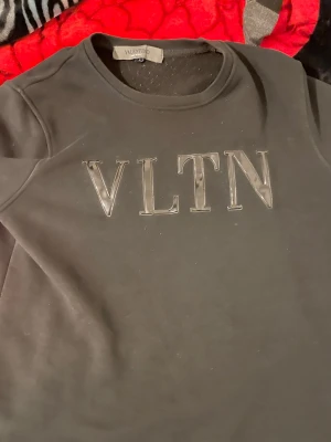Svart hoodie från Valentino VLTN - Snygg svart hoodie från Valentino med VLTN-logga i stora bokstäver på bröstet. Klassisk rund halsringning och mjukt material som känns skönt mot huden. Perfekt för dig som gillar stilrena och exklusiva plagg med tydlig logga.