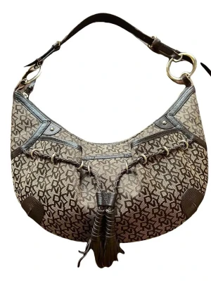 Brun DKNY axelremsväska med tofs - Säljer en snygg axelremsväska från DKNY i brunt och beige med klassiskt monogrammönster. Väskan har detaljer i mörkbrunt läder och en dekorativ tofs framtill. 