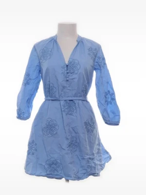 Blå broderad kortklänning med knappar - Söt ljusblå kortklänning med broderade blommor, v-ringning och knappar framtill. Klänningen har trekvartsärm och ett matchande bälte i midjan. Perfekt för sommarens alla tillfällen.