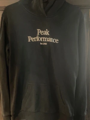 Svart hoodie Peak Performance - Snygg svart hoodie från Peak Performance med vit logga broderat på bröstet. Hoddien saknar fläckar samt hål. 