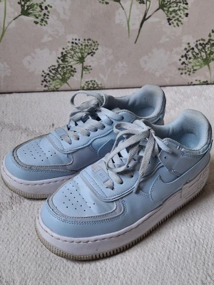 Nike Air Force 1 Pastellblå sneakers - Snygga Nike Air Force 1 sneakers i pastellblått med vita detaljer.
