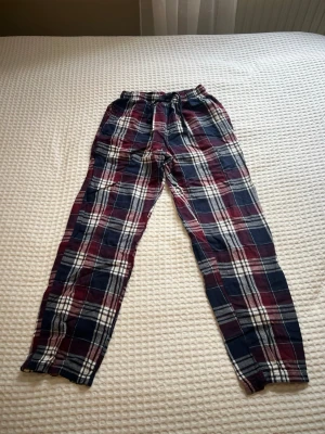 Rutiga pyjamasbyxor från Gekås - Mysiga pyjamasbyxor med rutigt mönster i vinrött, mörkblått och vitt. Säljer för att de är för små för mig.