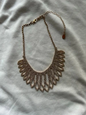 Guldigt statementhalsband med pärlor - Helt oanvändt halsband från Ur&Penn med gnistrande pärlor. Halsbandet har justerbar kedja och stängs med karbinhake. Perfekt för att lyfta vilken outfit som helst med extra bling och cool design.