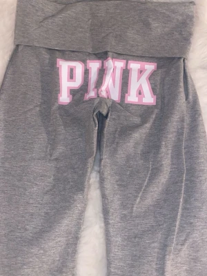 Grå yoga pants från PINK, Victorias secret  - Säljer ett par grå yogapants från PINK med bred linning och utsvängda ben. Byxorna har stor rosa och vit PINK-logga bak på rumpan och är gjorda i mjukt, stretchigt material som är perfekt för chill dagar. Supersnygga och bekväma att ha på sig. Nypriset är 700kr men säljer billigare💓💓🥰dessa är aldrig använda. 