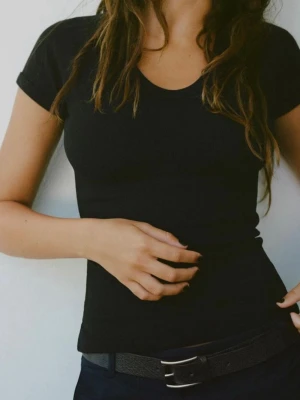 Svart ribbad v-ringad t-shirt från Zara - En svart t-shirt från Zara med v-ringning och korta ärmar. Slimpassform och liten i storlek, skulle säga en XXS, inte S. Aldrig använd. 