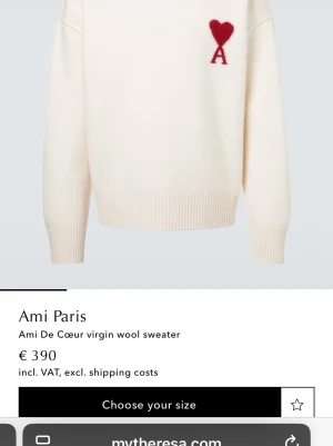 Vit stickad tröja Ami Paris - Vit stickad tröja från Ami Paris med röd hjärt- och A-detalj på bröstet. Tröjan har rund hals, ribbstickade muddar och är tillverkad i mjuk virgin wool. Perfekt för dig som gillar stilrena och trendiga plagg.