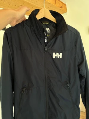 Helly Hansen Vindjacka  - Riktigt snygg mörkblå vindjacka från Helly Hansen. 10/10 skick. Hör av dig vid intresse. 