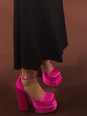 Platåpumps i starkt rosa sammet - Säljer ett par statement pumps i starkt rosa sammet med hög platå och bred klack. Skorna har rund tå och justerbar ankelrem med spänne. Perfekta för dig som vill sticka ut och älskar färg och höga klackar.