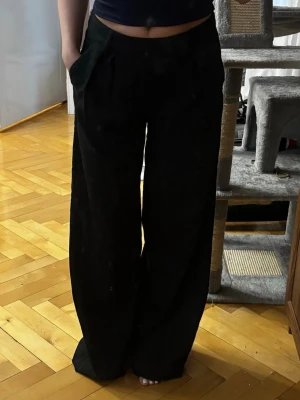 Svarta vida kostymbyxor låg midjade - Säljer ett par svarta mjukisbyxor med breda ben och hög midja. 