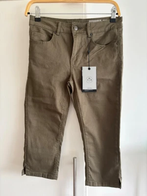 Capri byxor strl S - Snygga capri byxor från Vero Moda i modellen Mid Rise Slim. Byxorna har klassisk femficksdesign, smal passform och slitsar vid bensluten. Tillverkade i ett mjukt bomullsmaterial med stretch för extra komf