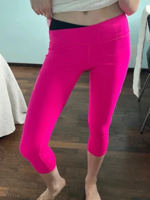 Hor pink capris - Säljer ett par riktigt snygga knallrosa leggings i 3/4-längd. De har hög midja och sitter tight för en smickrande passform. Perfekta för dig som vill sticka ut med färg! Materialet känns stretchigt och bekvämt.