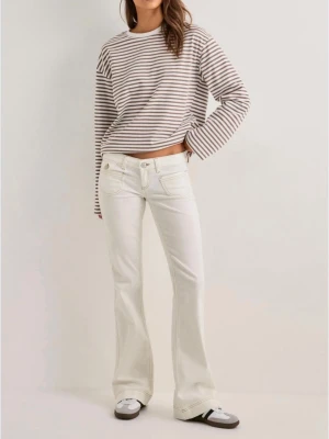 Vita bootcut jeans med låg midja - Snygga vita bootcut jeans med låg midja och klassiska fem fickor. Jeansen har vida ben och är tillverkade i ett mjukt denimtyg som ger en avslappnad men trendig look. Perfekta för dig som vill ha en retroinspirerad stil.