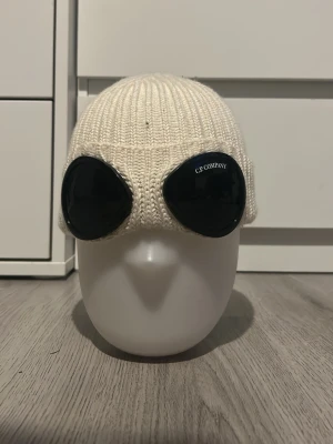 Vit cp company - Säljer en stilren vit stickad cp company mössa i mjukt material. Klassisk modell med uppvikt kant som passar perfekt till kalla dagar. Enkel att matcha med olika outfits