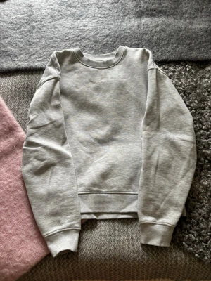 Ljusgrå basic sweatshirt - En stilren ljusgrå sweatshirt med rund halsringning och ribbade muddar vid ärmslut och nederkant. Tröjan är enkel och passar perfekt till jeans eller mjukisbyxor. Materialet känns mjukt och bekvämt mot huden.
