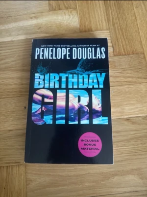 Birthday Girl av Penelope Douglas - Säljer boken 'Birthday Girl' av Penelope Douglas. Omslaget är svart med blå och lila text och motiv av en kvinna i vatten. Pocketbok med engelskt språk och etikett om bonusmaterial. Perfekt för dig som gillar romantisk och dramatisk skönlitteratur.