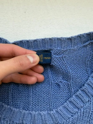 Blå kabelstickad tröja Polo Ralph Lauren -  Polo Ralph Lauren kabelstickad tröja – blå – storlek S    Säljer en äkta Polo Ralph Lauren kabelstickad tröja i en riktigt fin blå färg. Klassisk modell som alltid är efterfrågad.    Storlek: S (passar även XS–M beroende på önskad passform)    Skick:   • Mycket bra skick   • Inga hål eller slitningar   • Ren och redo att användas    • Broderad logga på bröstet   • Tjock och kvalitativ stickning   • Perfekt till både vardag och clean outfits