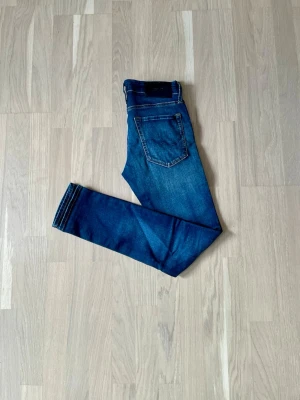 Mörkblå skinny jeans med stretch - Säljer ett par mörkblå jeans med klassisk femficksdesign och smal passform. Jeansen har en lätt tvättad look och är tillverkade i stretchigt denimtyg för extra komfort. Perfekta för en avslappnad och trendig stil.