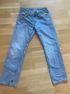 Ljusblå raka jeans med låg midja - Säljer ett par ljusblå jeans med rak passform och låg midja. Jeansen har klassiska fem fickor, bälteshällor och dragkedjegylf. Materialet är denim i bomull och färgen har en snygg tvättad look.