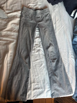 Grå bootcut stretch jeans - Snygga grå bootcut jeans med klassisk femficksdesign och normal midja. Jeansen har en lätt utsvängd passform nedtill och är tillverkade i ett mjukt denimtyg som ger en avslappnad vibe. Perfekta att matcha med sneakers eller boots för en cool look.