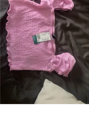 Ljusrosa topp - Supersöt ljusrosa croppad topp från med puffiga korta ärmar och smockad struktur. Toppen har vågig kant nertill för en extra gullig vibe💞Den är ny med prislapp, storlek L men skulle mer säga typ S/M