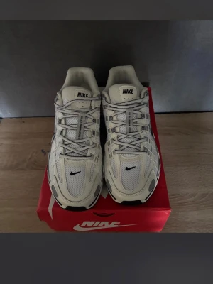 Nike vita sneakers med svart swoosh - Snygga vita Nike sneakers med svart swoosh och detaljer. Ovandelen är i mesh och syntet för bra andningsförmåga. Sulan är vit med svarta inslag och ger skön dämpning. Klassisk snörning och sportig look som passar till många outfits.