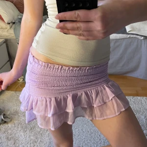 Lila volangkjol - Supersöt kjol i lila med volangkant. Jag brukar vika ner kjolen utan problem men den kan även användas som en topp. Kjolen har smock i midjan för en bekväm passform och dubbla lager volanger nedtill. Perfekt för dig som vill ha en trendig look.