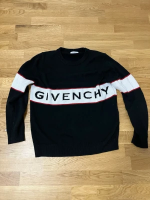 Svart stickad tröja från Givenchy - Snygg svart stickad tröja från Givenchy med vit panel och röd kant längs bröstet och ärmarna.  den är strl S och den är använd men inte så mycket den har inga skador eller något sånt tar byten och pris kan diskuteras 