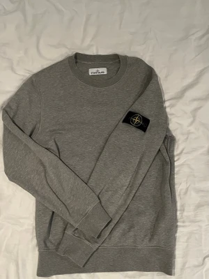 Stone Island Sweatshirt  - Jag säljer nu min gråa sweatshirt från Stone Island då den inte kommer till användning längre. Storlek M. Bild 2 visar en liten defekt på tröjan. Vid frågor eller funderingar skriv.