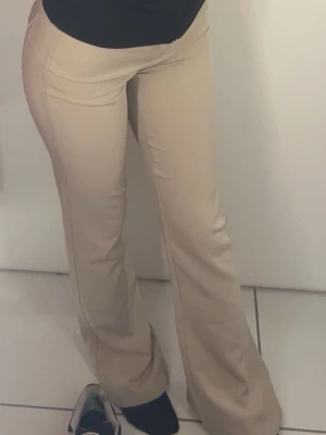 Beiga utsvängda kostymbyxor - Säljer ett par beiga kostymbyxor med utsvängda ben. Från Gina tricot köpta ett år sen inte kommi till användning. Jätte liten fläck på ena fikan därav priset men är ej märkbart. I storlek s.