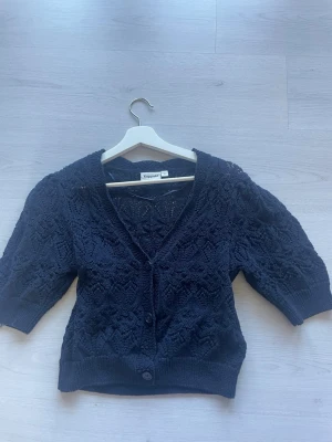 Mörkblå virkad kofta från Kappahl - Snygg mörkblå kofta från Kappahl med virkat mönster och kortare ärmar. Använd två gånger och passar väldigt snyggt med vitt linne! 