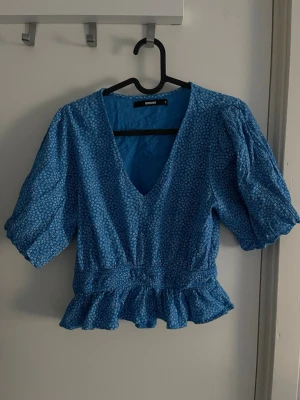 Blå volang sommar set  - Sött blått volang sommar set med en topp som är urringad och en omlott kjol som man kan knyta i midjan. Perfekt nu inför sommaren 