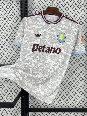 Aston Villa bortatröja Adidas - Säljer en Aston Villa bortatröja från Adidas med grått och vitt kamouflagemönster. Tröjan har vinröda detaljer vid krage och ärmslut, klubbmärke på bröstet och Betano-logga framtill. Perfekt för fotbollsfans som vill sticka ut på läktaren.