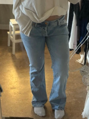 Ljusblå lågmidjade bootcut jeans - Jeansen har en avslappnad passform och är tillverkade i denim. Lågmidjade och utsvängd, supersnygg färg nu till våren. Midjemått 37 cm och Innerbenslängd:80 cm