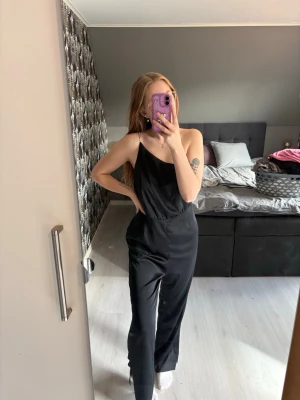 Satin jumpsuit - H&M - Snygg svart jumpsuit med glittrigt axelband ifrån H&M 🖤✨ Storlek 40, materialet är satin. Endast använd en gång på nyår - som ny, super fint skick!!  Jag är 167cm lång för referens 🥰