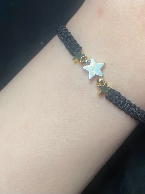 Svart makraméarmband med stjärnor - Snyggt svart makraméarmband med tre stjärnformade pärlor i mitten. Justerbar knytning för perfekt passform. Perfekt accessoar för dig som gillar unika detaljer och stjärntema.