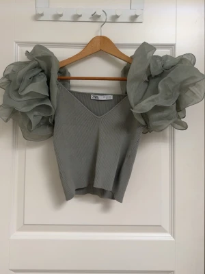 Olivgrön topp med volangärmar  - En olivgrön topp med stora, voluminösa puffärmar. 