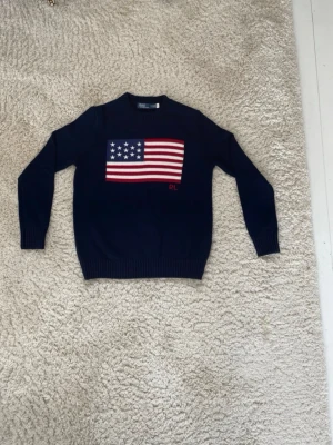 Ralph Lauren USA flagga - Säljer en mörkblå Polo Ralph Lauren stickad tröja med USA-flagga 🇺🇸  Storlek: S (märkt SP) Skick: Väldigt fint skick, knappt använd Färg: Mörkblå med broderad flagga och RL-logo framtill Passform: Klassisk och stilren  Perfekt till både vardag och lite finare outfits ✨ Äkta Polo Ralph Lauren.  Hör av dig vid frågor eller fler bilder!