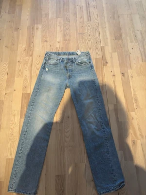 Acne studio jeans herr storlek 29/32 - Säljer ett par ljusblå jeans med rak passform och klassisk femficksdesign. Jeansen har en liten slitning vid ena fickan och en patch bak i midjan. Tillverkade i denim med en avslappnad look, perfekta för en casual stil.