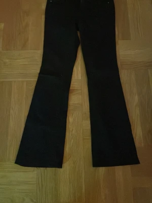 Svarta bootcut byxor från true religion - Säljer ett par svarta bootcut byxor från true religion med klassisk ficka bak och tydlig logga på lappen. Byxorna har en snygg utsvängd passform och är gjorda i ett slitstarkt bomullsmaterial. Perfekt för dig som gillar retrovibbar och vill sticka ut. DOM ÄR UPPSYDDA!!