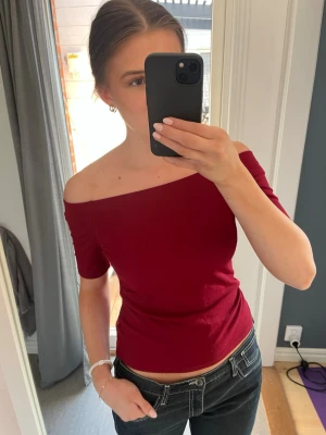Vinröd oneshoulder topp - Snygg vinröd topp med oneshoulder-design och korta ärmar.  Endast använd någon gång 