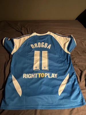 Chelsea matchtröja Drogba 2012 Adidas - Säljer en blå Chelsea matchtröja från Champions League-finalen 2012 med Drogba och nummer 11 på ryggen. Tröjan har vita detaljer, Adidas-logga, Samsung som sponsor och ClimaCool-material för bra ventilation. Perfekt för fotbollsfans!