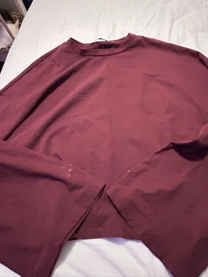 Vinröd långärmad topp i bomull - En enkel och stilren vinröd långärmad topp med rund halsringning. Tillverkad i mjuk bomull som känns skön mot huden. Perfekt att matcha med jeans eller kjol för en clean look.