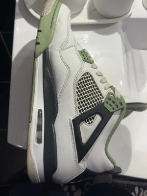 Air Jordan 4 Retro vit/olivgrön - Säljer ett par Air Jordan 4 Retro sneakers. Storlek 44, rengjorda känns som i nytt skick. Pris kan diskuteras