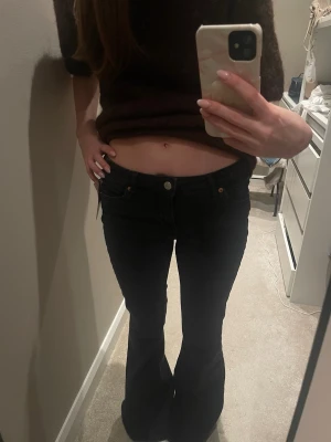 Svarta bootcut jeans - Säljer ett par svarta bootcut jeans med hög midja och klassisk femficksdesign. Jeansen har utsvängda ben och stängs med knapp och dragkedja. Perfekta för en trendig och avslappnad stil. Jeansen är i stoleken 26/32. Skriv såklart till mig ifall du har några frågor eller funderingar!❤️