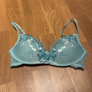 Intimissimi - Turkos spets-bh med blommönster - Turkos bh med vadderade kupor och push-up. Spetsdetaljer längs nederkanten och justerbara axelband. Köpt i Göteborg på intimissimi butiken. Knappt använd men säljer då den är för liten. Har en liten mörkblå fläck (se bild 4). Storlek 80C men passar nog mindre också. 