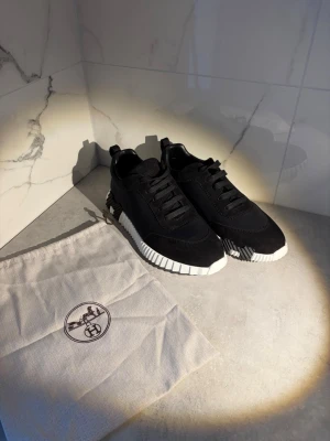 Svarta H sneakers med vit sula - Säljer ett par svarta H sneakers med cool kontrasterande vit sula och svarta skosnören. Ovandelen är i en mix av mocka och textil, med snygga detaljer. Vid frågor skriv gärna😁