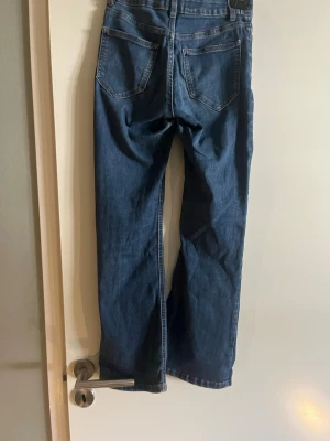 Blå jeans från Lindex Freja - Klassiska blå jeans från Lindex modell Freja. Jeansen hsr bootcut, fem fickor och normal passform. Perfekta till vardagslooken och tillverkade i bomull för en skön känsla.