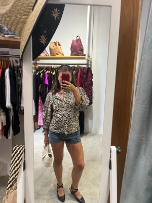 Leopardmönstrad blus från Zara - Säljer en leopardmönstrad blus från Zara med puffiga långärmar och rund halsringning. Blusen har en luftig passform men ändå figursydd kring midjan och knappar framtill. Materialet är lätt och känns skönt mot huden, perfekt för att sticka ut i mängden.