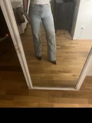 Ljusblå raka jeans med hög midja - Säljer ett par ljusblå jeans med rak passform och hög midja. Jeansen har klassiska fem fickor och stängs med dragkedja och knapp. 